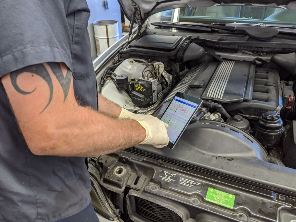 Technician using DVI on tablet while inspecting car